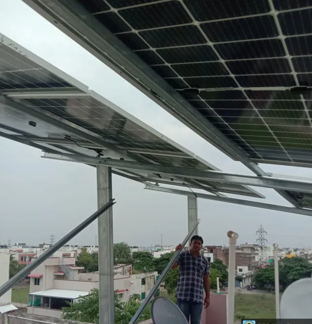 Underside of a raised solar array on a Bhopal terrace, with the owner standing below it