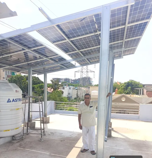 Tall PPGI frame carrying panels over a terrace, with the owner standing underneath