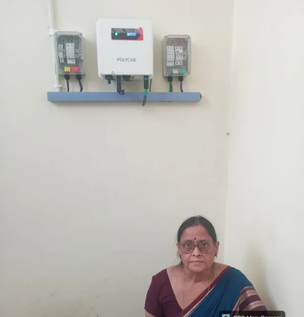 Wall-mounted inverter between a DC box and an AC box, with the owner seated below